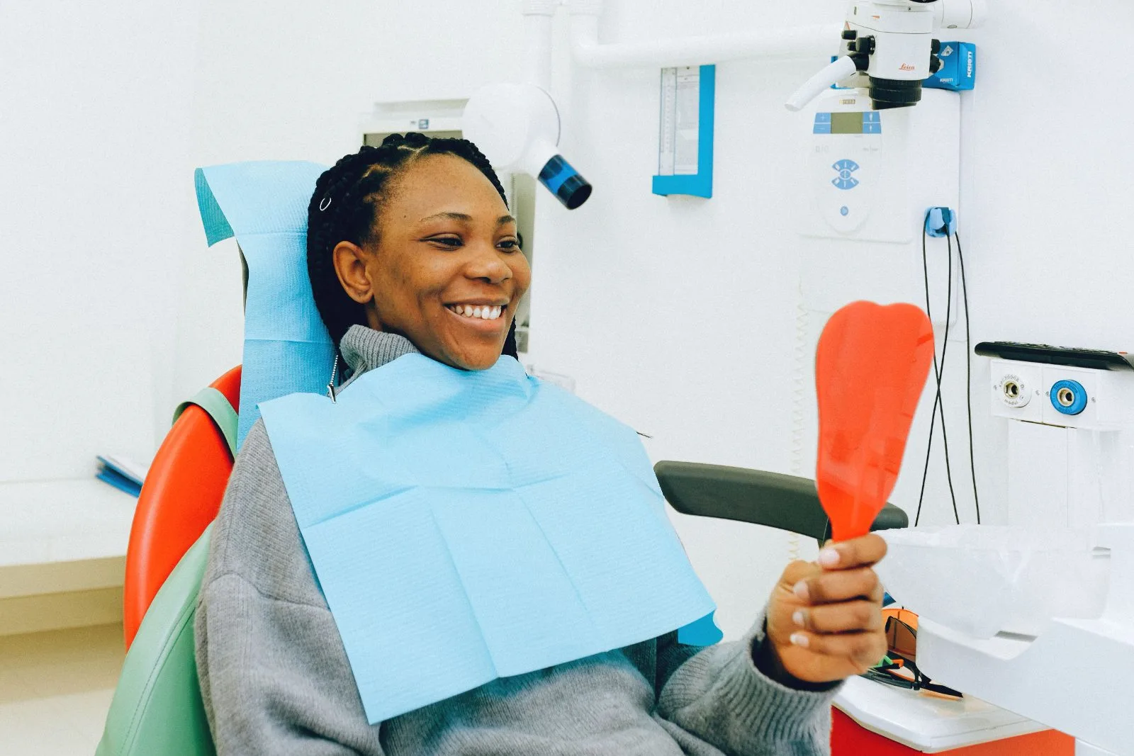 Patient smiling while checking her teeth in a hand mirror after treatment